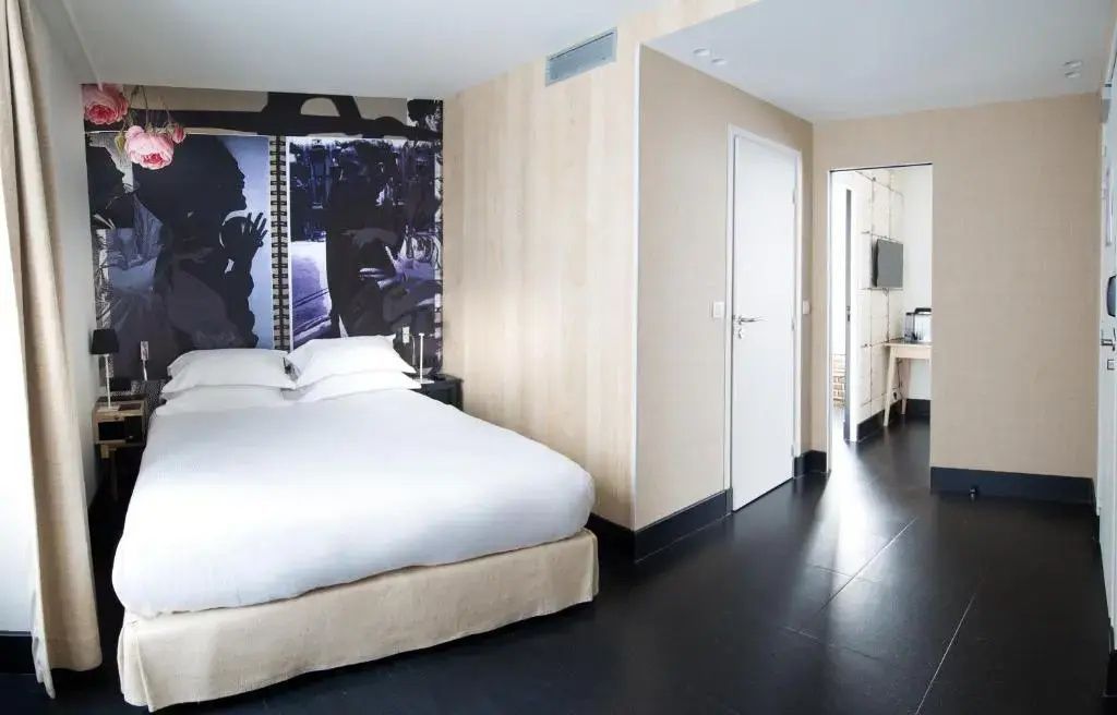 Schlafbereich mit großem Doppelbett, weißer Bettwäsche und Holzwand.