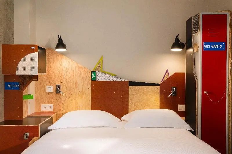 Doppelbett mit weißen Kissen und einer modisch gestalteten Holzwand mit Lampen.
