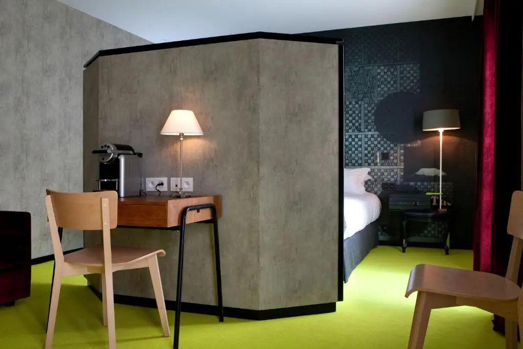 Schreibtisch mit Kaffeemaschine und Lampe neben einer Raumtrenner Wand im Hotelzimmer.
