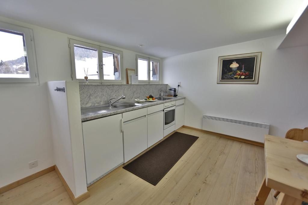 Einbauküche mit hellen Schränken, Steinarbeitsplatte und Holzfußboden in einem Hotelzimmer.