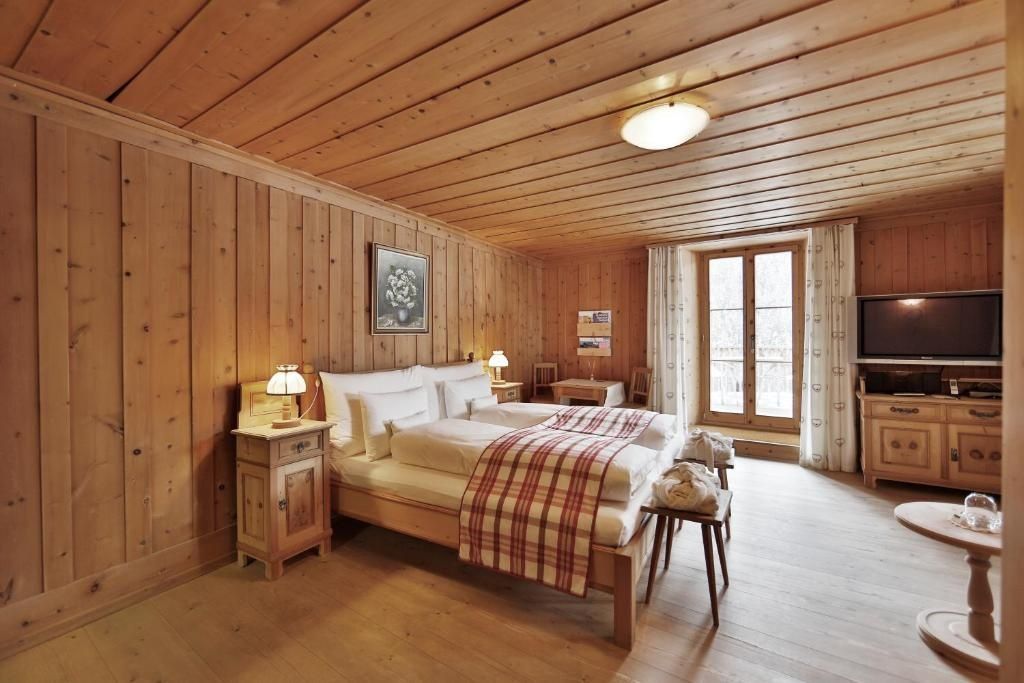 Rustikales Hotelzimmer mit kompletter Holzverkleidung, Doppelbett und Holzmöbeln