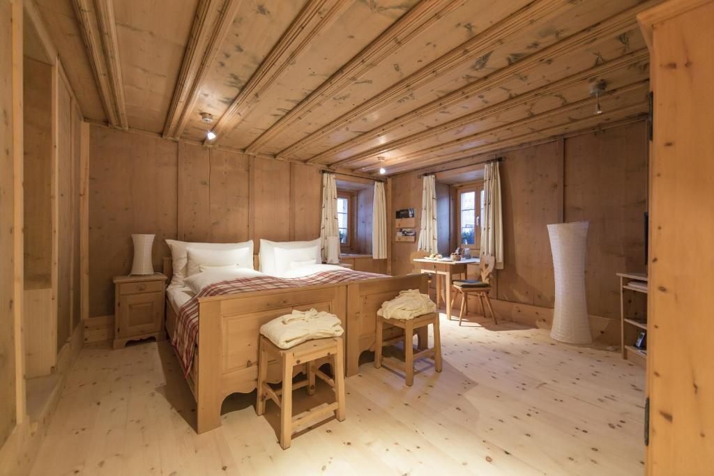Schlafzimmer mit Arvenholzverkleidung, Holzdoppelbett und Schreibtisch am Fenster