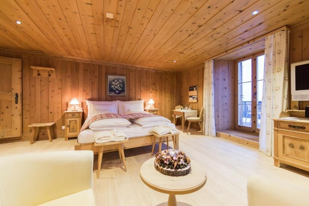 Schlafbereich mit Holzdecke, Holzvertäfelung, Doppelbett und kleinem Tisch.