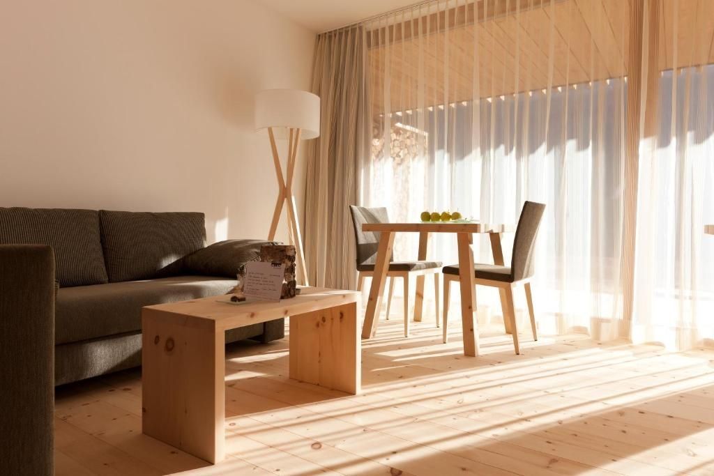Sitzbereich im Hotelzimmer mit Holztisch, Stühlen, Sofaecke und hellem Fensterlicht.