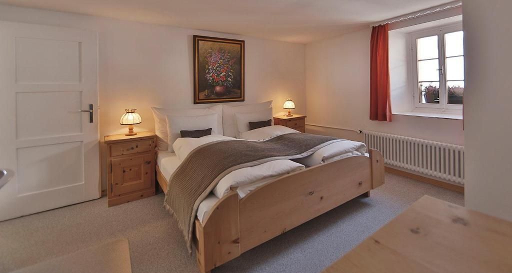 Doppelbett aus Holz mit weißer Bettwäsche, Nachttischen und einem Gemälde an der Wand.