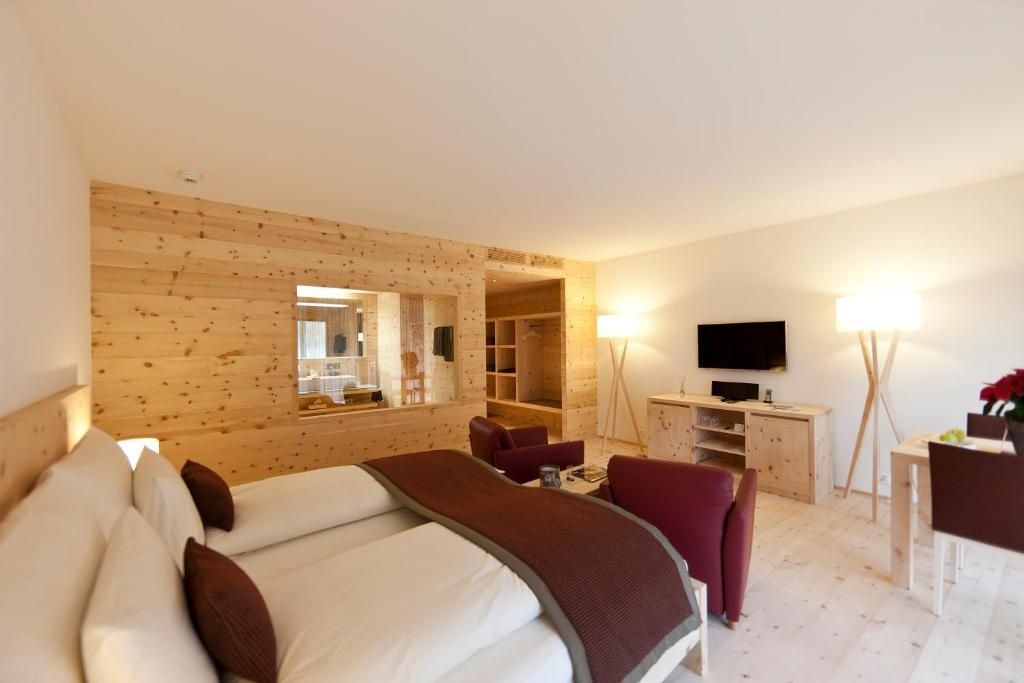 Sicht auf den Schlafbereich mit Holzverkleidung, Fernseher und Durchblick zum Bad.