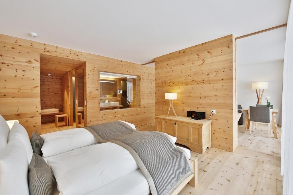 Großzügiges Schlafzimmer aus hellem Arvenholz mit Doppelbett und Kommode.