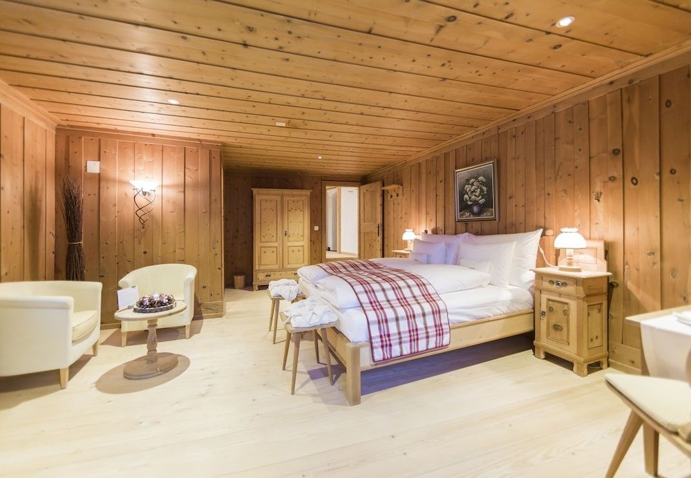 Schlafzimmer mit Holzvertäfelung, Doppelbett und Sesseln im Engadiner Stil.