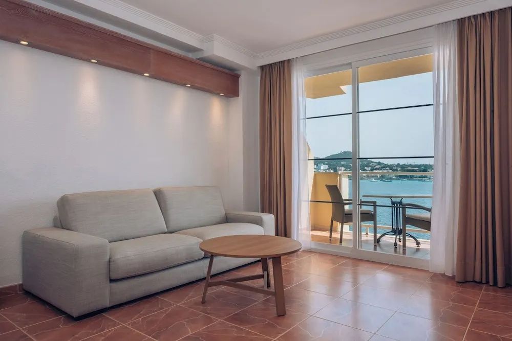 Sofa im Wohnbereich neben einer großen Glasfront mit Blick auf den Balkon und das Meer.