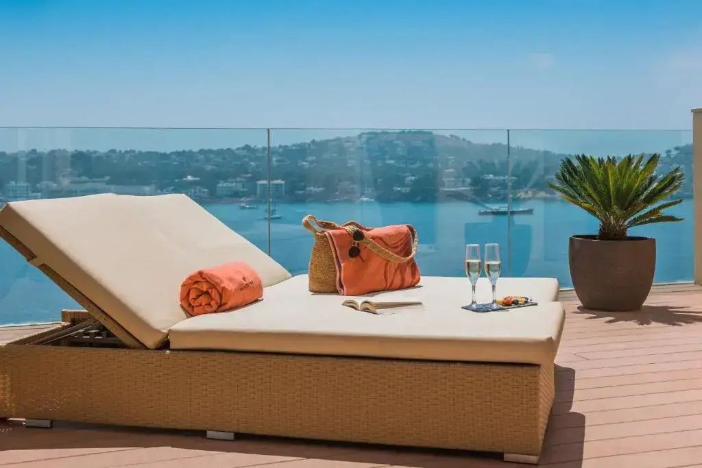 Sonnenliege auf einer Terrasse mit Glasgeländer und freiem Blick auf das Meer