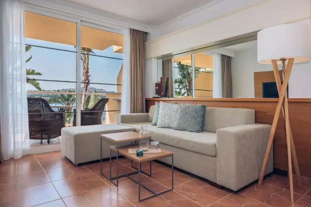 Wohnbereich mit hellem Sofa, Couchtischen und Glasschiebetür zur Terrasse.