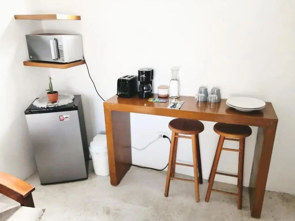 Küchenbereich im Zimmer mit Holzbar, zwei Barhockern, Kaffeemaschine und Minibar