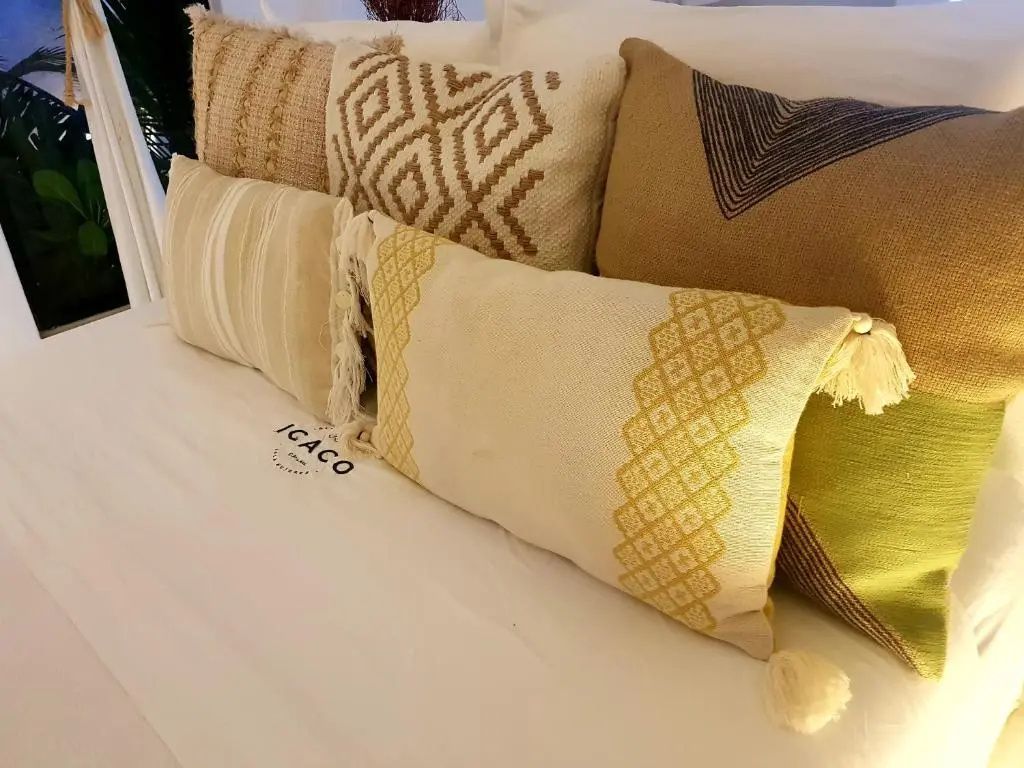 Mehrere bestickte Zierkissen mit verschiedenen Mustern auf einem weiß bezogenen Bett.