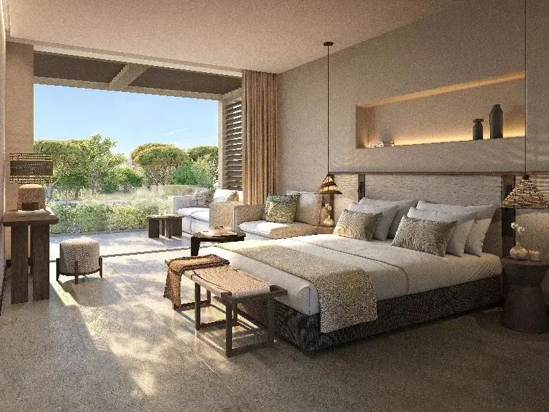 Helles Hotelzimmer mit Doppelbett, Sitzbereich und Übergang zur überdachten Terrasse.