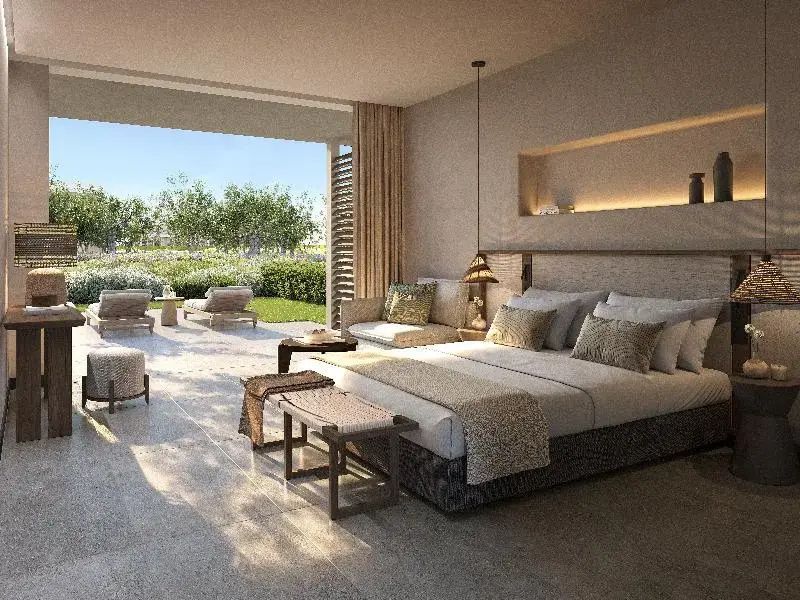 Modernes Zimmer mit großem Bett, Sitzgelegenheiten und Terrasse mit Gartenblick.