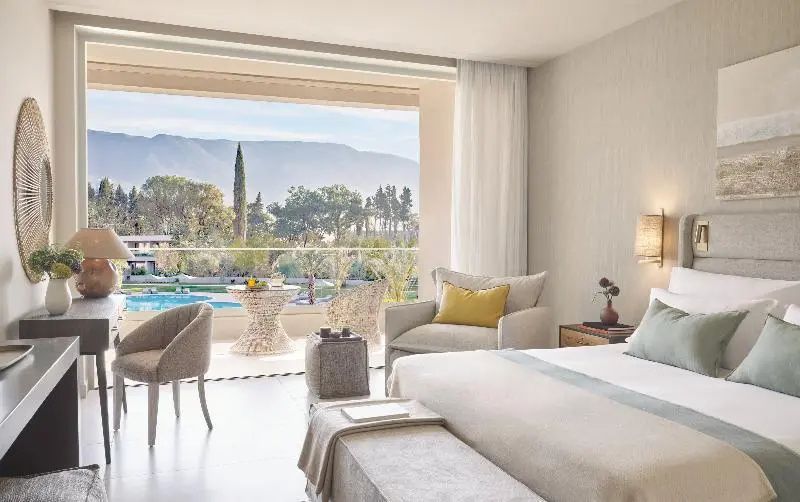 Hotelzimmer mit Ausblick über die Poolanlage auf die dahinter liegenden Berge.