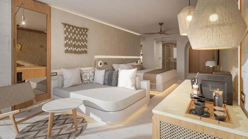 Sitzbereich mit grauem Sofabett und Couchtisch vor dem Schlafbereich im Zimmer.