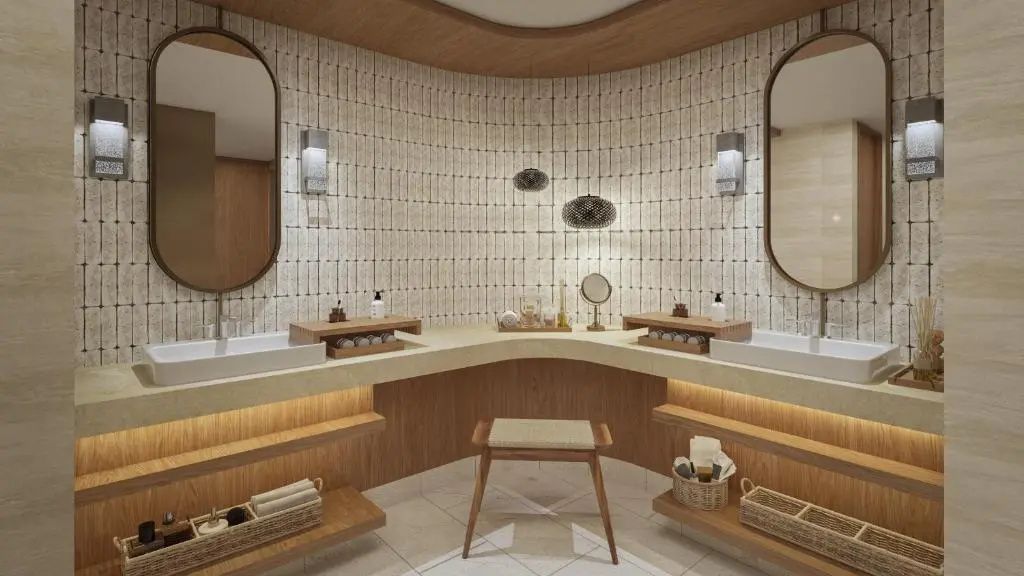 Badezimmer mit Doppelwaschtisch, zwei Spiegeln, Hocker und gefliesten Wänden.