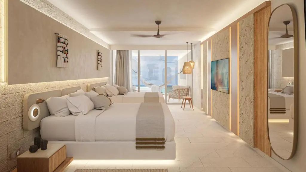 Hotelzimmer mit zwei Betten, Fernseher an der Wand und Balkon mit Hängematte vor blauem Meer.