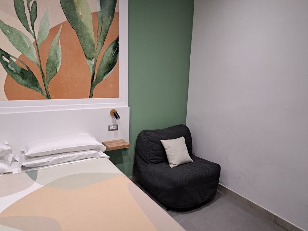 Sitzgelegenheit im Hotelzimmer neben einem weiß bezogenen Doppelbett.