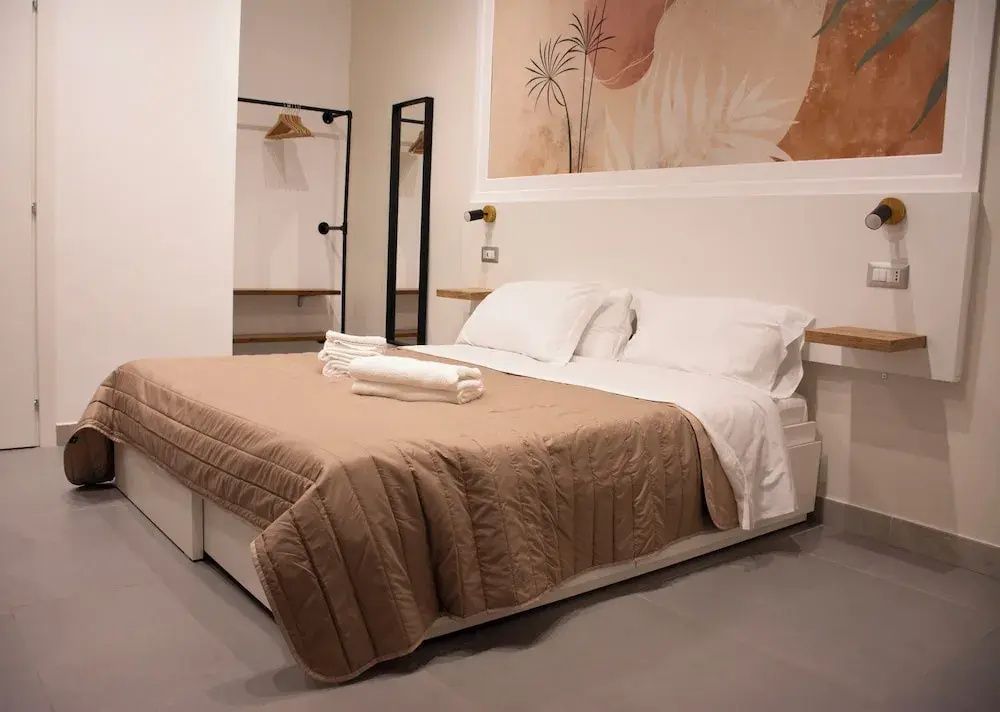 Doppelbett mit brauner Tagesdecke und Handtüchern im hellen Zimmer.