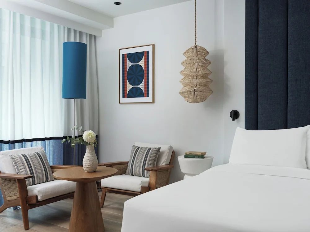 Sitzbereich im Zimmer mit Holzstühlen, einem runden Tisch, einer Stehlampe und Wandkunst.