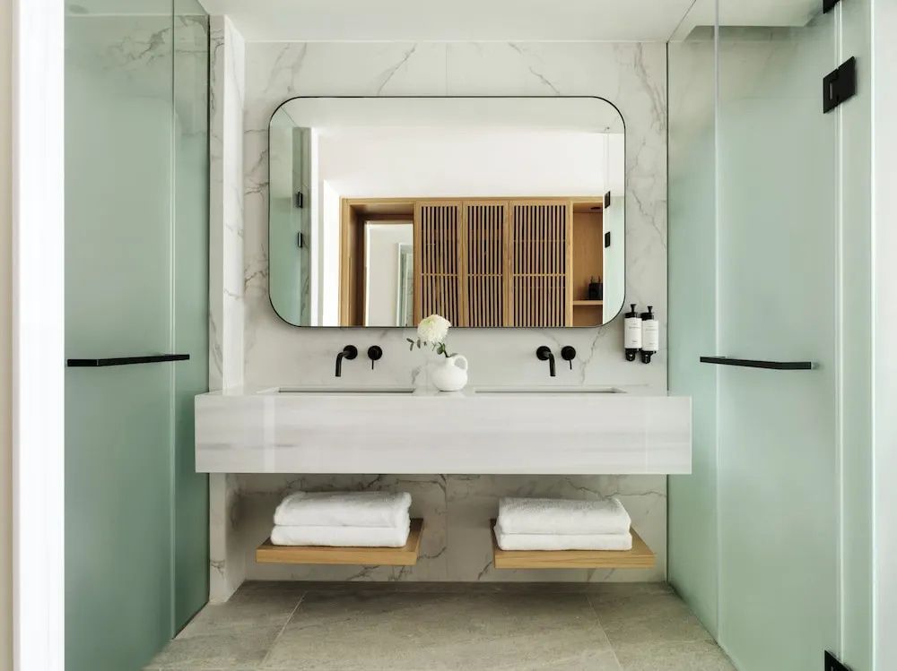 Modernes Badezimmer mit breitem Waschtisch, großem Spiegel und frischen Handtüchern.