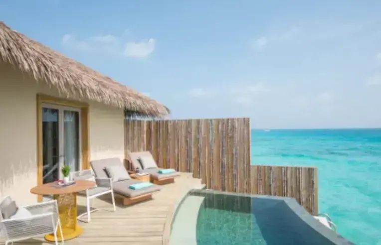 Sonnendeck einer Villa mit kleinem Pool, zwei Liegestühlen und Blick auf das türkise Meer.