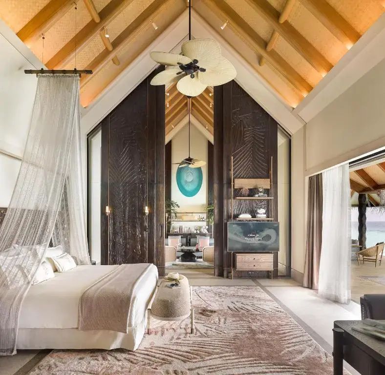 Schlafzimmer einer Villa mit hohem Holzgebälk, Doppelbett und Vorhängen