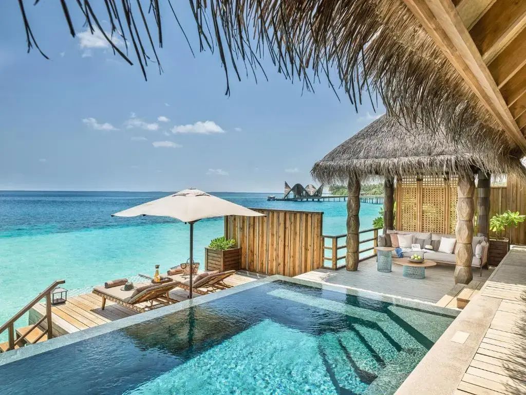 Überdachter Außenbereich einer Überwasservilla mit privatem Pool, Sitzgruppe und Sonnendeck.