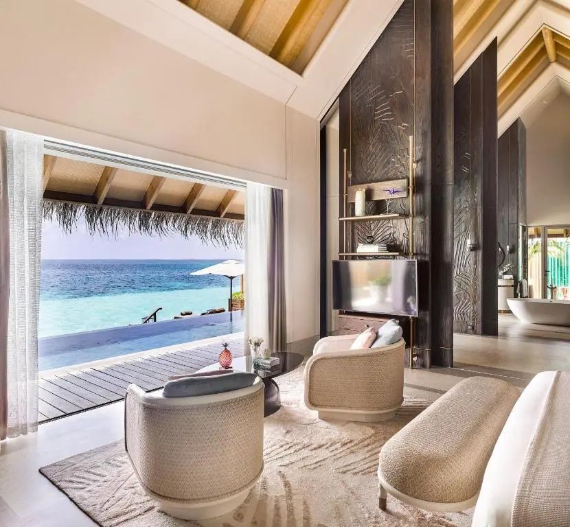 Zimmer mit Blick durch geöffnete Schiebetüren auf die Terrasse, den Pool und das Meer.
