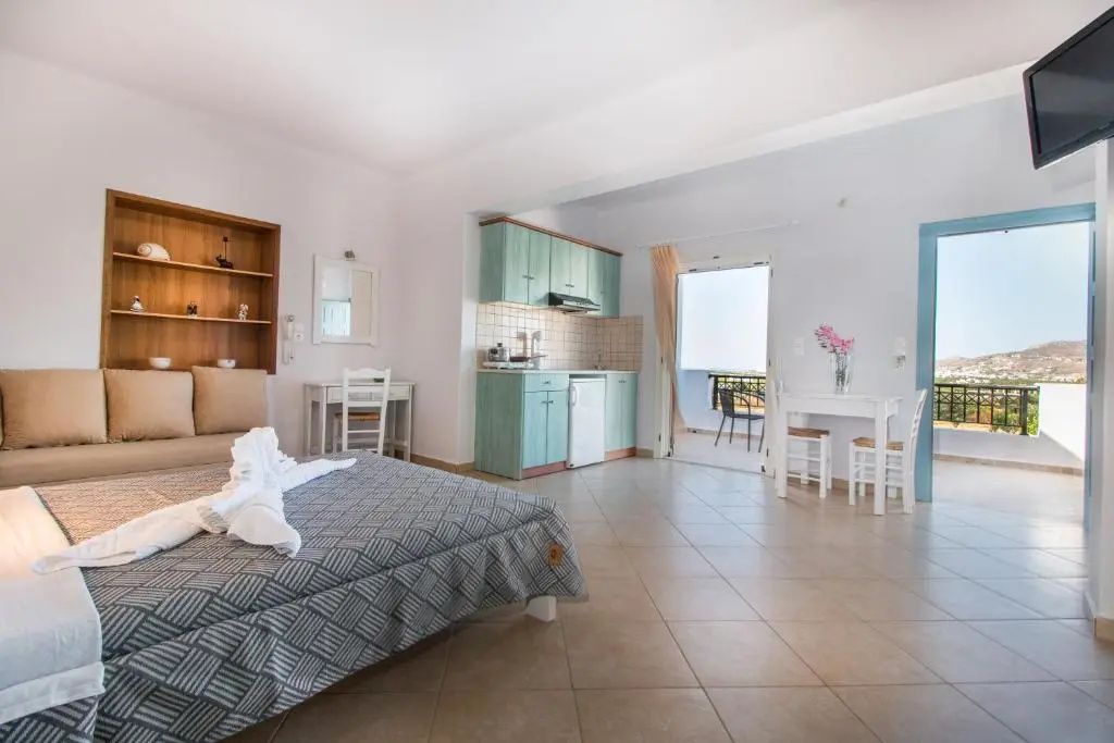 Geräumiges Apartment mit Doppelbett, mintgrüner Küchenzeile und Zugang zum Balkon.