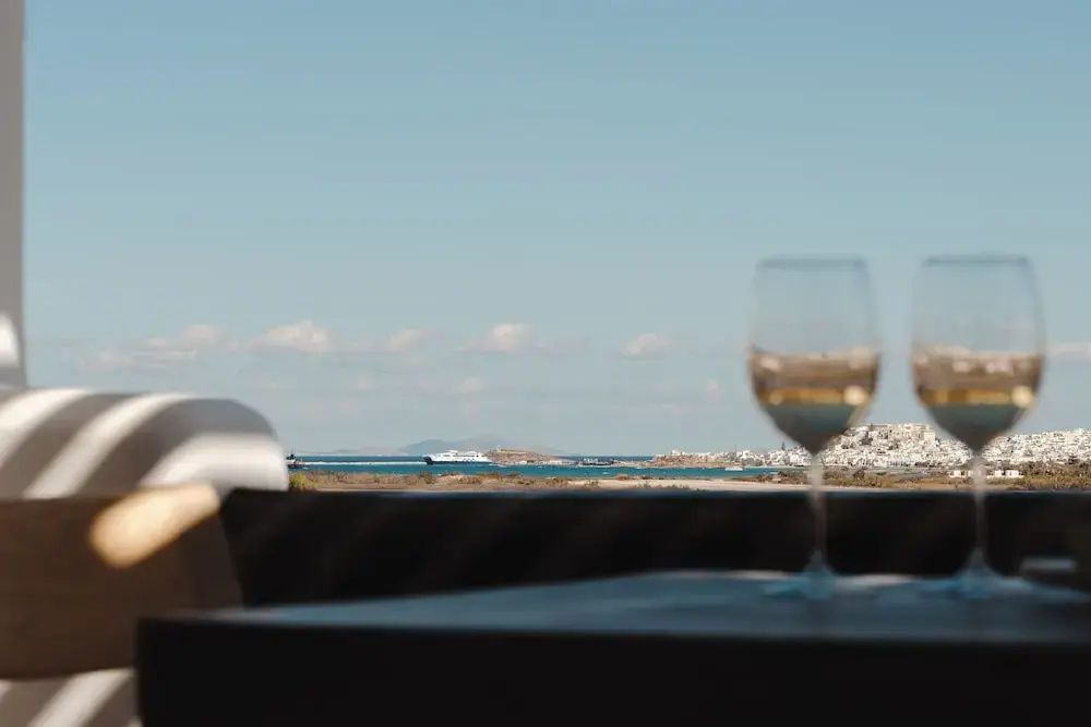 Nahaufnahme eines Weinglases auf einem Tisch mit Blick auf die Küste im Hintergrund.