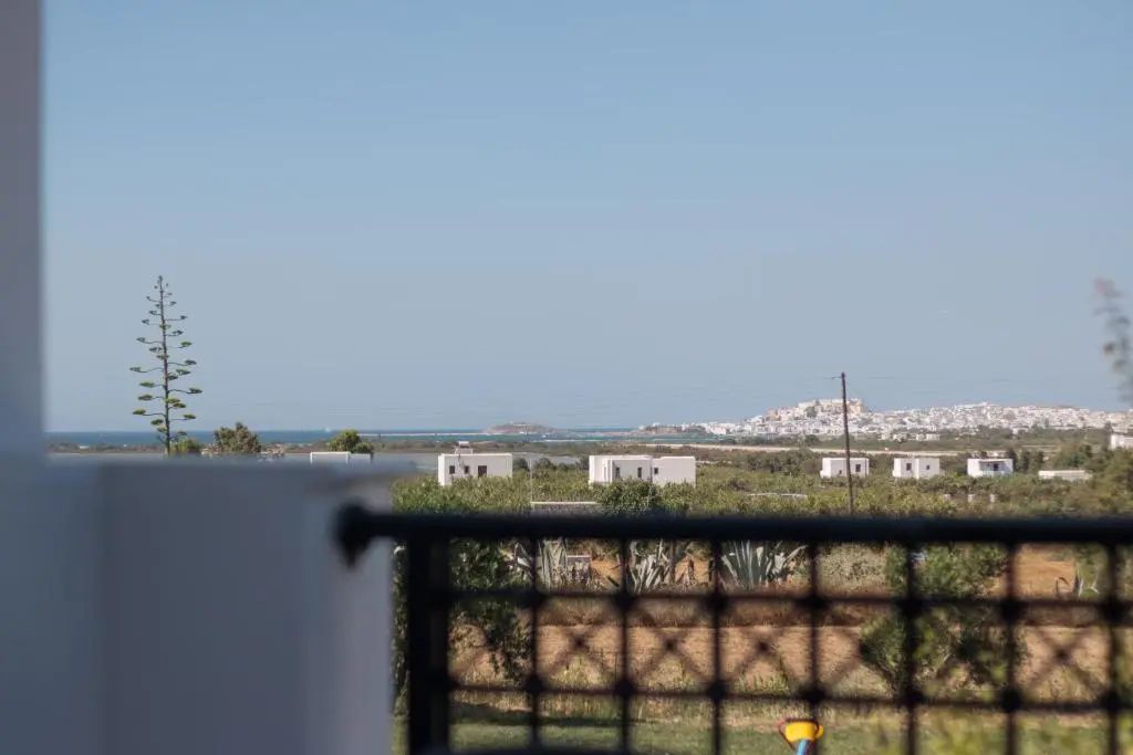Blick vom Balkon über grüne Felder und weiße Häuser hin zum blauen Meer.