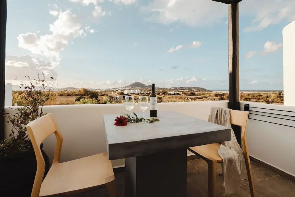 Tisch und Stühle auf einem Balkon mit Blick auf die umliegende Landschaft.