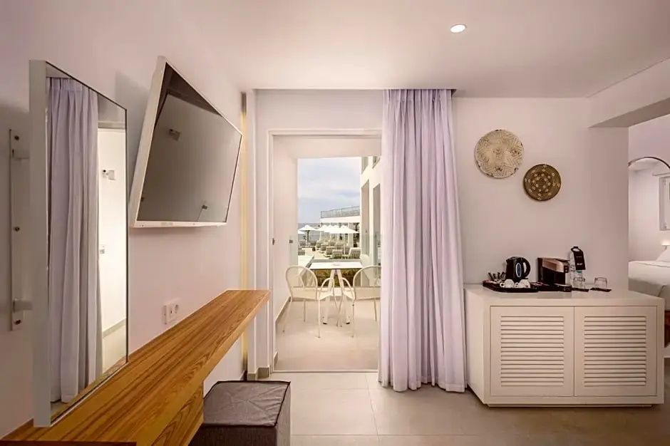 Helles Hotelzimmer mit Flachbildfernseher an der Wand und Zugang zum Balkon