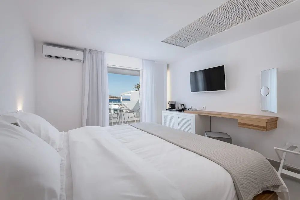 Schlafzimmer mit Doppelbett, Fernseher an der Wand und Balkon mit Meersicht