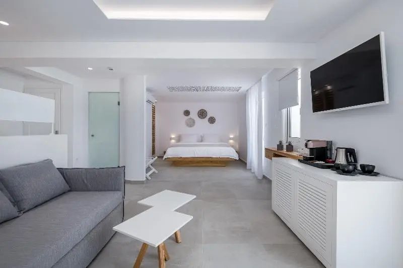 Blick durch das helle Hotelzimmer mit grauer Couch vorne und Doppelbett an der hinteren Wand.