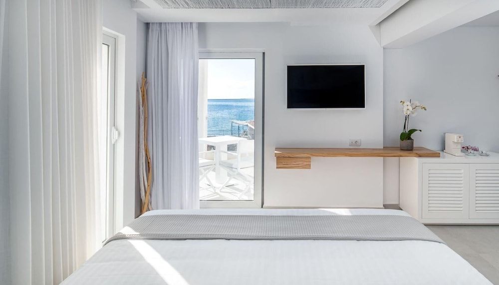 Blick aus dem Hotelzimmer über das Bett hinweg auf den Balkon und das Meer.
