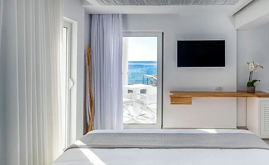 Fensterfront im Zimmer mit Ausblick auf den eigenen Balkon und das offene Meer.