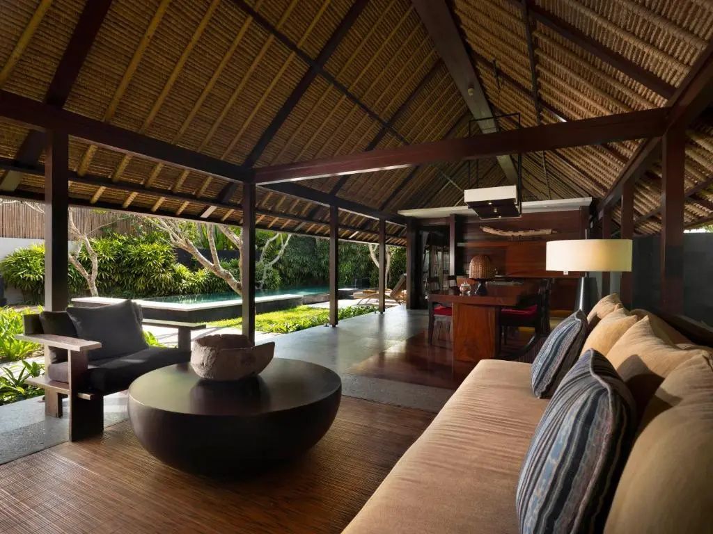Offener Wohnbereich einer Villa mit Reetdach, Sofa und Blick in den Garten