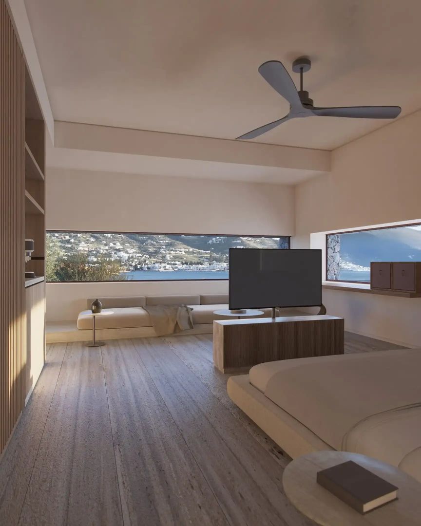 Zimmer mit Panoramafenster und freiem Blick auf die Bucht und die hügelige Küstenlandschaft.