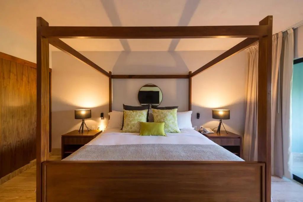 Doppelbett als Himmelbett aus Holz mit Nachttischen und zwei Lampen im Hotelzimmer.