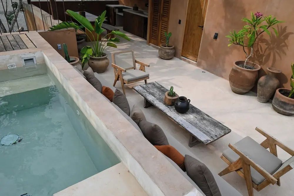 Außenbereich mit kleinem Pool, Holztisch, Sesseln und Topfpflanzen im Innenhof.