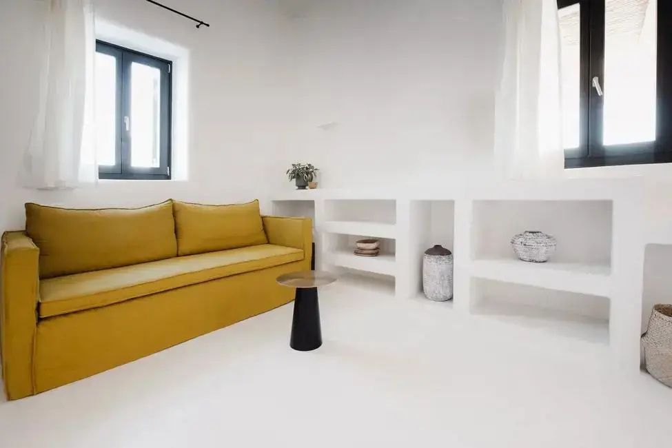 Wohnbereich mit gelbem Sofa, kleinem Beistelltisch und in die Wand integrierten Regalen