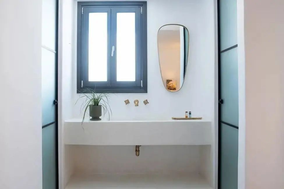 Weißer Waschtisch mit goldenen Armaturen und einem ovalen Spiegel im Badezimmer.