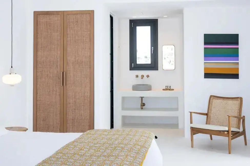 Blick auf einen Holzschrank, einen integrierten Waschtisch mit Fenster und einen Stuhl.