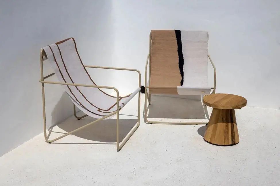 Zwei moderne Sessel aus Stoff und ein kleiner Holztisch auf einer weißen Terrasse.