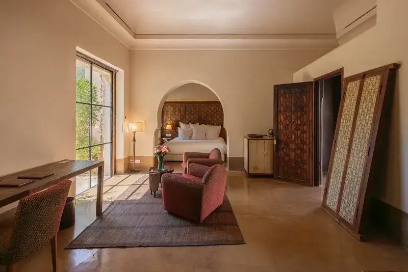 Geräumiges Hotelzimmer mit Sitzbereich, Holztür und Bett in einer Nische.