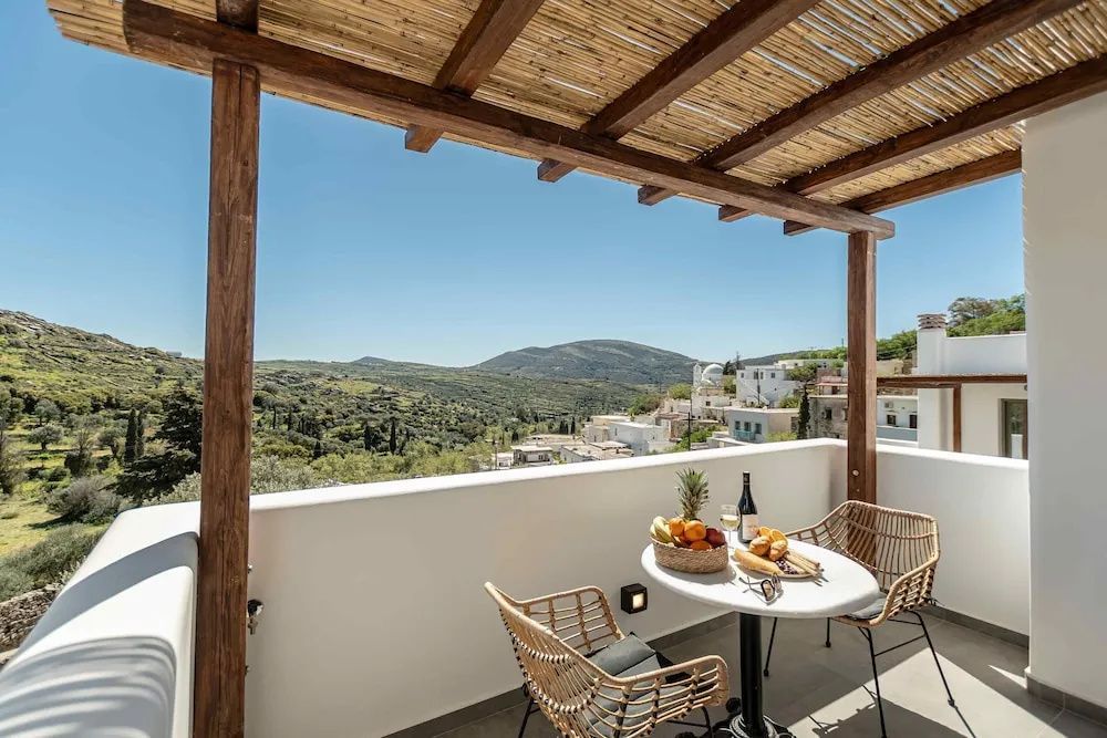 Terrasse mit Holzüberdachung, Sitzgelegenheit und Weitblick auf Hügel und Häuser.